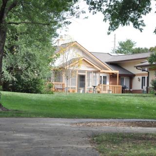 A suburban house with a large lawn and surrounding trees, featuring some ongoing construction or renovation work.