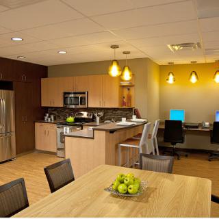 A modern kitchen and workspace area featuring sleek furniture, appliances, and a cozy dining setup.