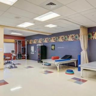 A well-equipped physical therapy room in a rehabilitation center with treatment tables and exercise equipment.