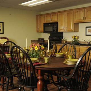 A warmly lit dining area with a wooden table set for a meal, featuring candles and dinnerware.