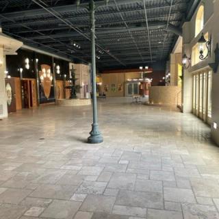 An empty indoor mall corridor with stores and decorative lighting.