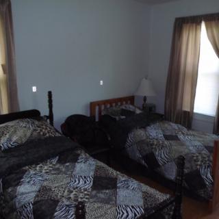 A bedroom with two twin beds, a lamp, and a window with curtains.