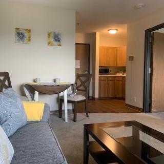 A cozy living room featuring a sofa, coffee table, and a small dining area leading to the kitchen.