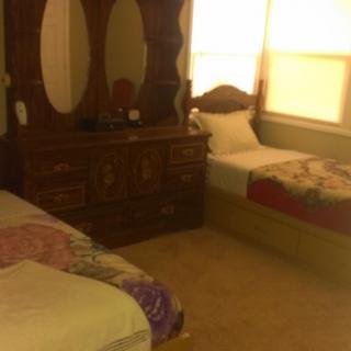 A bedroom with two beds and a wooden dresser with mirrors.