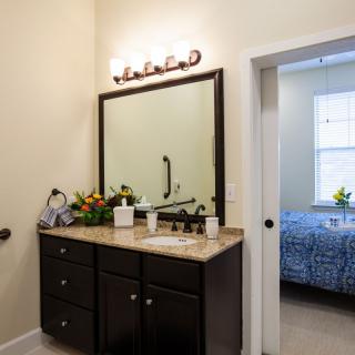 A well-lit bathroom featuring a dark wood vanity with a large mirror and modern light fixtures.