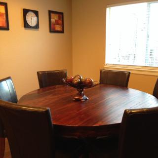 A cozy dining room with a round wooden table and chairs near a bright window.