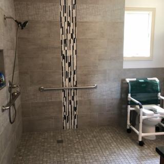 An accessible bathroom with a walk-in shower and a shower chair.