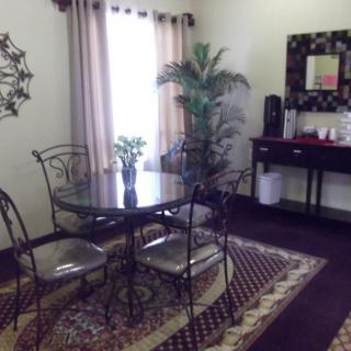 A cozy dining area with a glass table, metal chairs, and decorative plants.