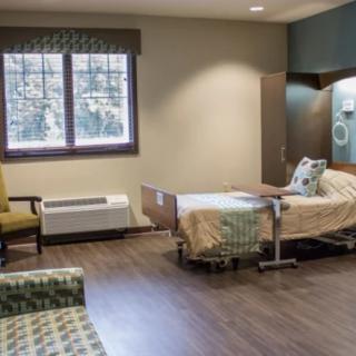 A hospital room with a bed, chair, and medical equipment.