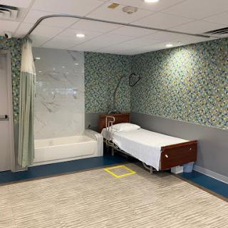 A clean and modern hospital room featuring a bed and a shower area.