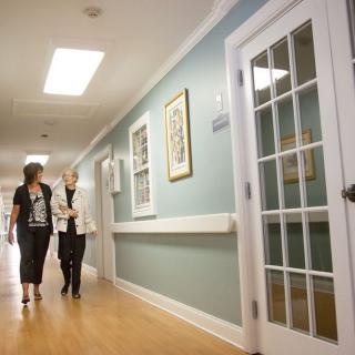 Two people walking and conversing in a well-lit hallway.