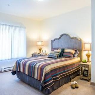 A cozy bedroom with a striped bedspread and warm lighting.