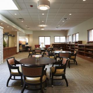 A spacious library interior with tables and chairs, surrounded by bookshelves.