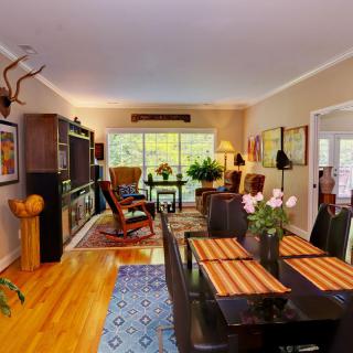 A cozy living room with a dining area featuring hardwood floors, eclectic decor, and ample natural light.
