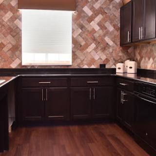 A modern kitchen featuring dark cabinets and a stylish tile backsplash.