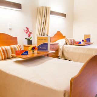 A cozy hotel room featuring two beds, decorative pillows, and a touch of floral elegance.