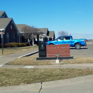 A scenic view featuring a building with a sign in front, accompanied by a blue truck parked nearby under a clear sky.