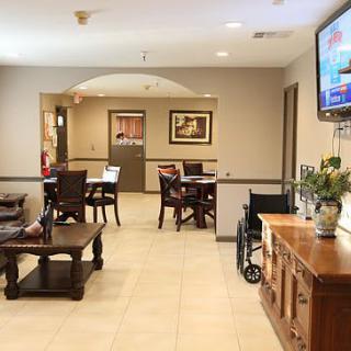 A cozy lobby or waiting area with tables, chairs, and a television.