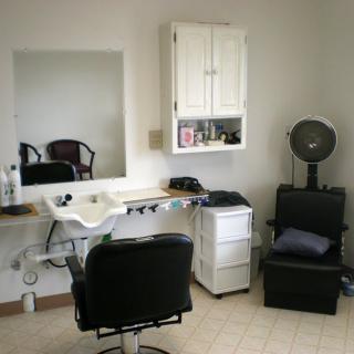 A cozy hair salon setup with a mirror, salon chair, sink, and hair dryer.