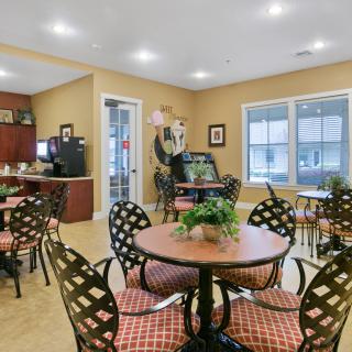 A cozy cafe with patterned chairs and tables, complete with indoor plants and warm lighting.