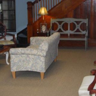 A cozy living room with a patterned couch, a lamp, and wooden stairs.