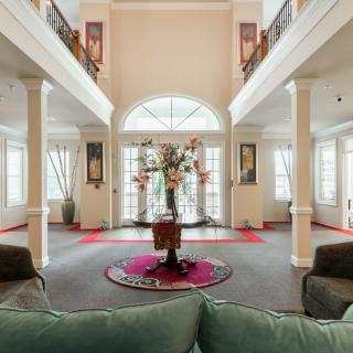 A spacious and elegantly decorated living room with large windows, arches, and pillars.