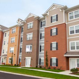 A modern, multi-story apartment building in a suburban area.