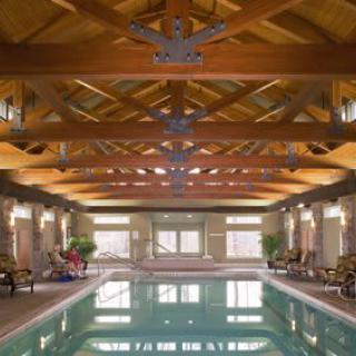 A luxurious indoor swimming pool featuring a wooden beam ceiling and elegant interior design.