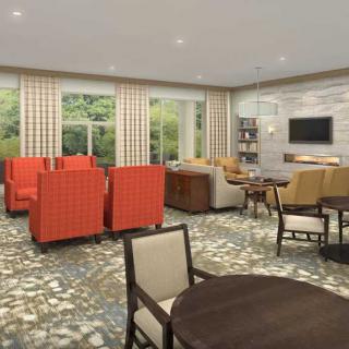 A modern living room with seating area, featuring orange chairs and a patterned carpet.