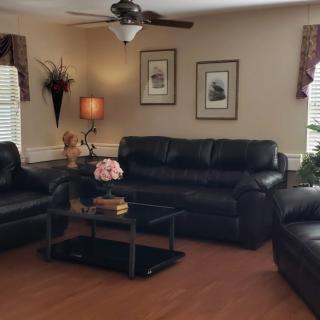 A cozy living room with dark leather sofas and a central coffee table.