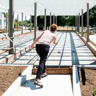 A woman playing bocce on an outdoor court.