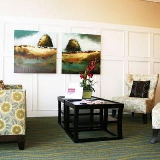 A cozy living room with modern decor, featuring two large pieces of artwork, a central table, and comfortable seating.