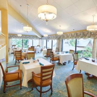 A bright and elegant dining area with neatly arranged tables and chairs, surrounded by large windows.