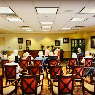 A group of elderly individuals seated in a meeting room for a presentation.