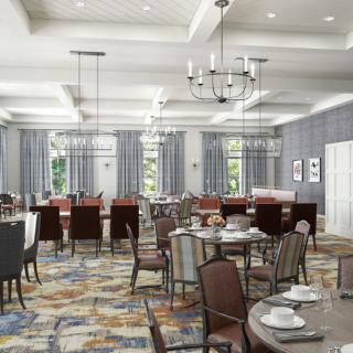 A spacious dining room with neatly arranged tables and chairs, featuring elegant chandeliers and a patterned carpet.