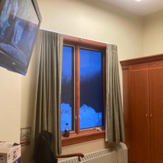 A cozy room featuring a television, warm wood tones, and a window revealing a serene winter scene.