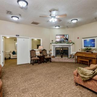 A cozy living room featuring a fireplace, sofa, and piano.