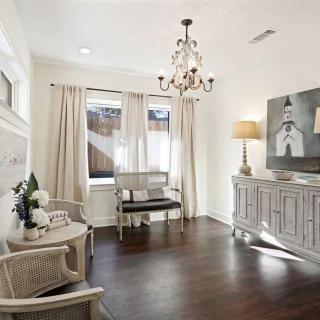 A cozy living room with elegant decor, featuring a chandelier and hardwood flooring.
