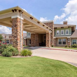 A modern residential building with a stone facade and landscaped entrance.