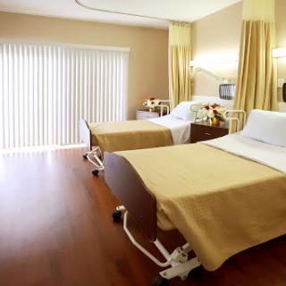 A modern hospital patient room featuring two beds with warm decor.