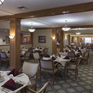 An elegant dining area with neatly arranged tables and chairs, featuring warm lighting.