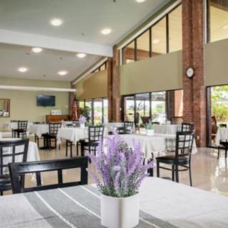 A spacious and modern dining area with neatly arranged tables and chairs, illuminated by natural light.