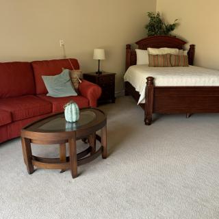 A cozy room featuring a red sofa, wooden bed, and small coffee table.