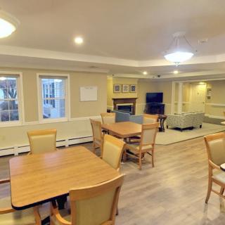 A cozy communal space with dining tables and a living area, featuring a fireplace and television.