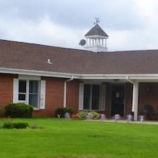 A brick suburban house with a neatly maintained lawn and a cupola on the roof.