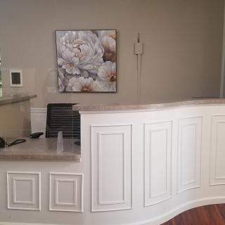 A modern reception desk area with elegant paneling and wall art.