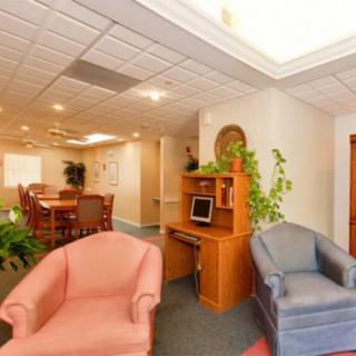 A bright office space with a meeting area, featuring a computer desk and comfortable seating.