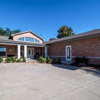 A suburban brick house with a spacious driveway under a clear blue sky.