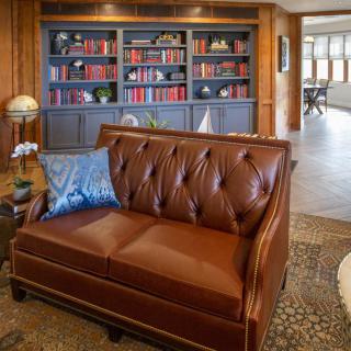 A luxurious living room featuring a leather sofa and an elegant bookshelf filled with red books.
