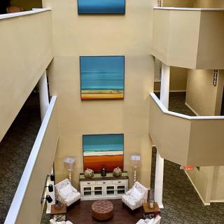 Modern atrium with colorful paintings and a cozy seating area.